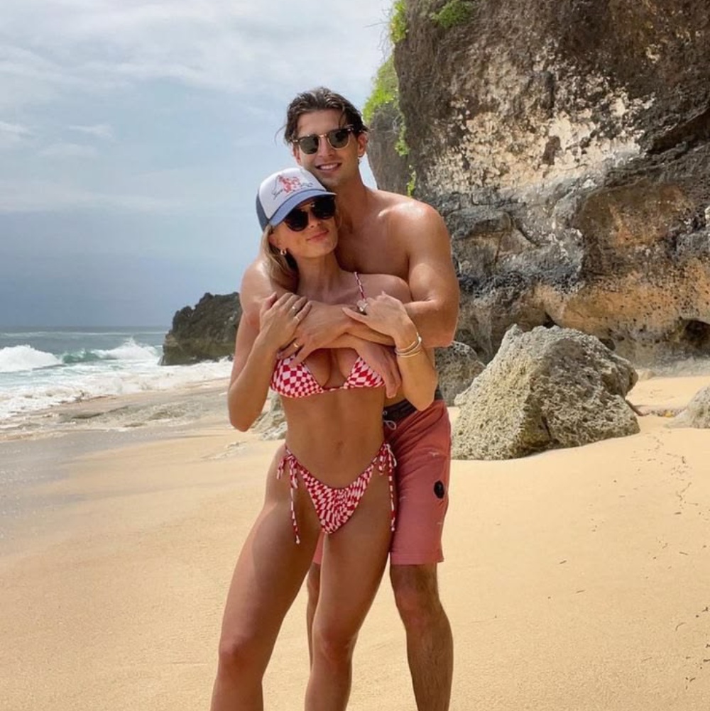 Couple embracing on a beach near rocky cliffs under cloudy sky for private outdoor intimacy