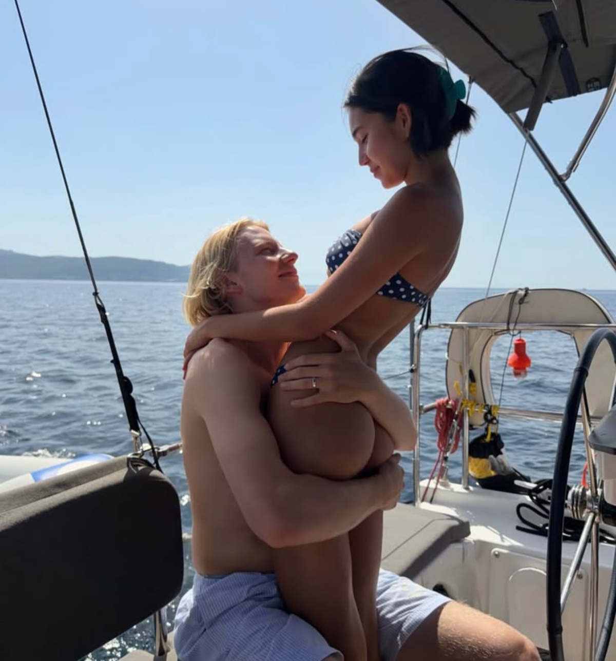 Couple on a sailboat embracing at sea showing intimate private moment away from daily life